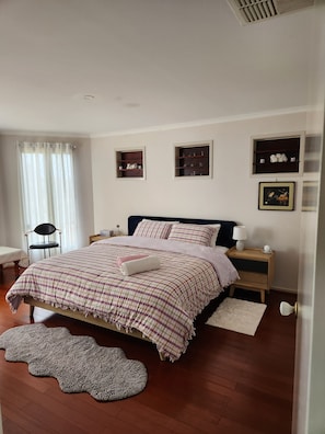 A bedroom with a bed, bedside tables, a chair, and a window with curtains. - Ultimate relaxation with convenient location (Manor Lakes)