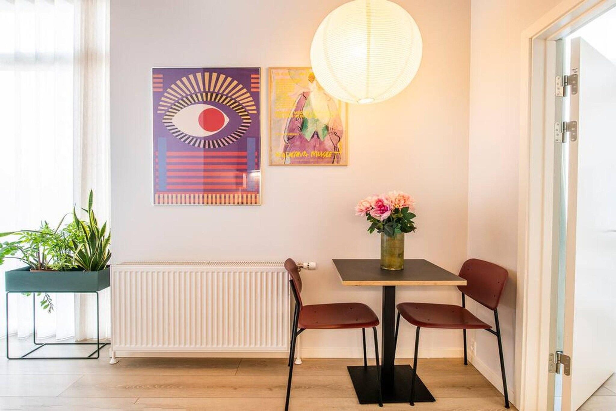 Ein moderner Essbereich mit Tisch, Stühlen, einer Zimmerpflanze und Bildern an der Wand.