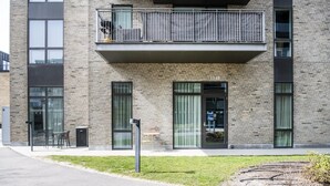 En modern byggnad med en fasad av tegel, stora fönster och en balkong med räcken av metall.