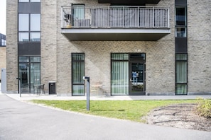 Un edifici modern amb façana de maó, grans finestres i un balcó amb barana metàl·lica.