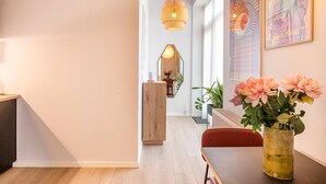 En modern inredning med trägolv, ett matbord med stolar, en vas med blommor och en hängande lampa.