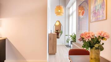 Ein modernes Interieur mit Holzboden, einem Esstisch mit Stühlen, einer Blumenvase und einer hängenden Leuchte.