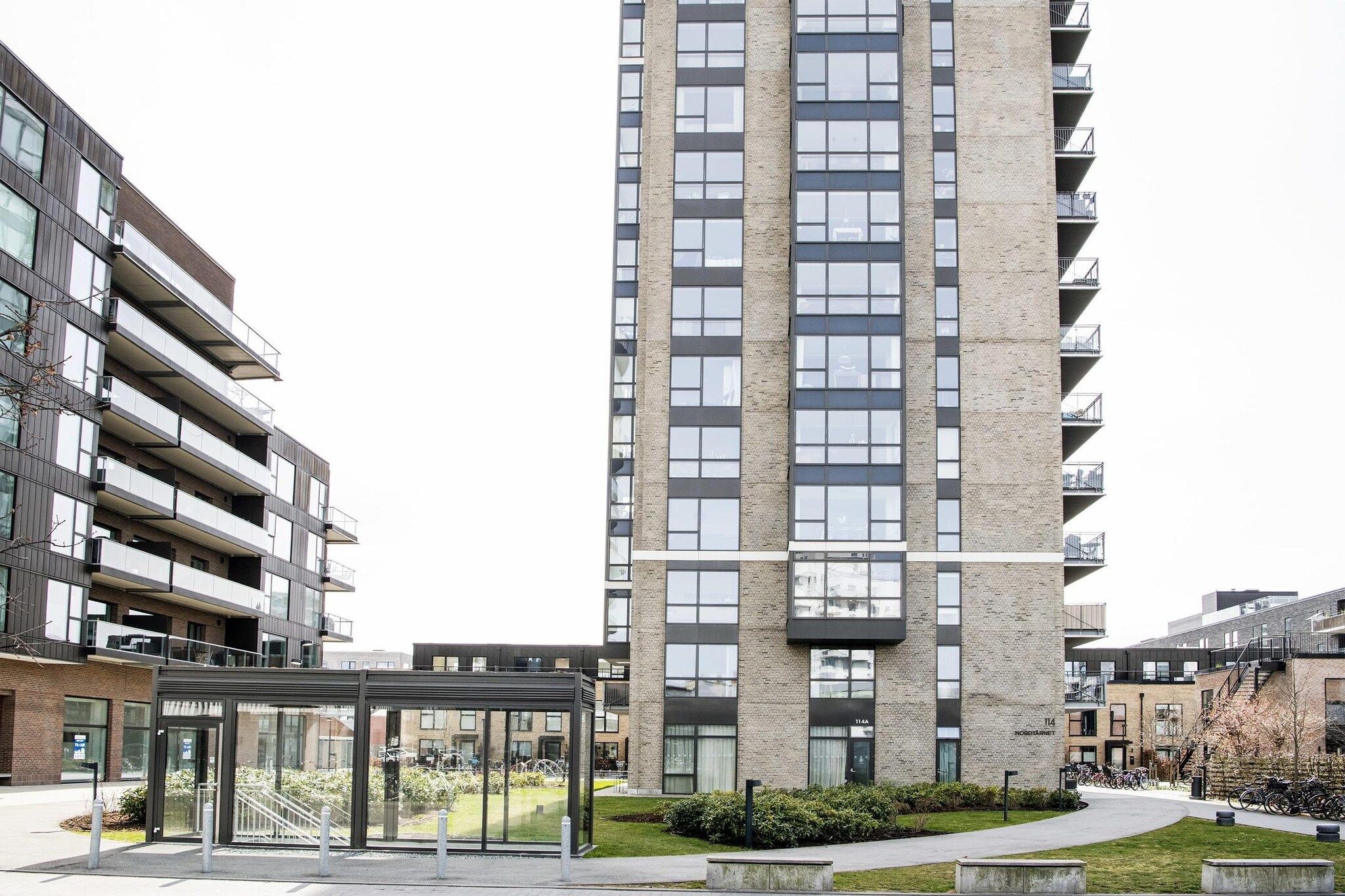 A modern multi-story residential building with balconies and a glass entrance.