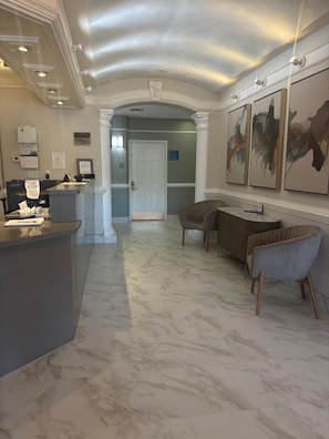 A reception area with a marble floor, a reception desk, and two armchairs. - La Quinta Inn Brownsville (Los Fresnos)