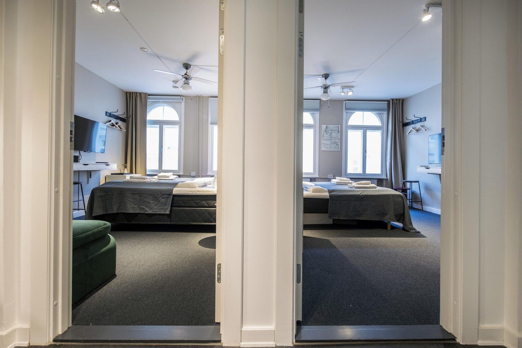 Spiegelbild eines Hotelzimmers mit zwei Betten, einem Schreibtisch und einem Sessel.