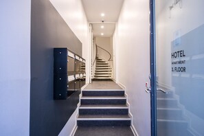 A hotel staircase leading to the third floor, with a glass door on the right indicating the hotel's location. - Historic Center Copenhagen Home (København)