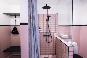 Et moderne badeværelse med bruser, toilet og håndklædetørrestativ.
