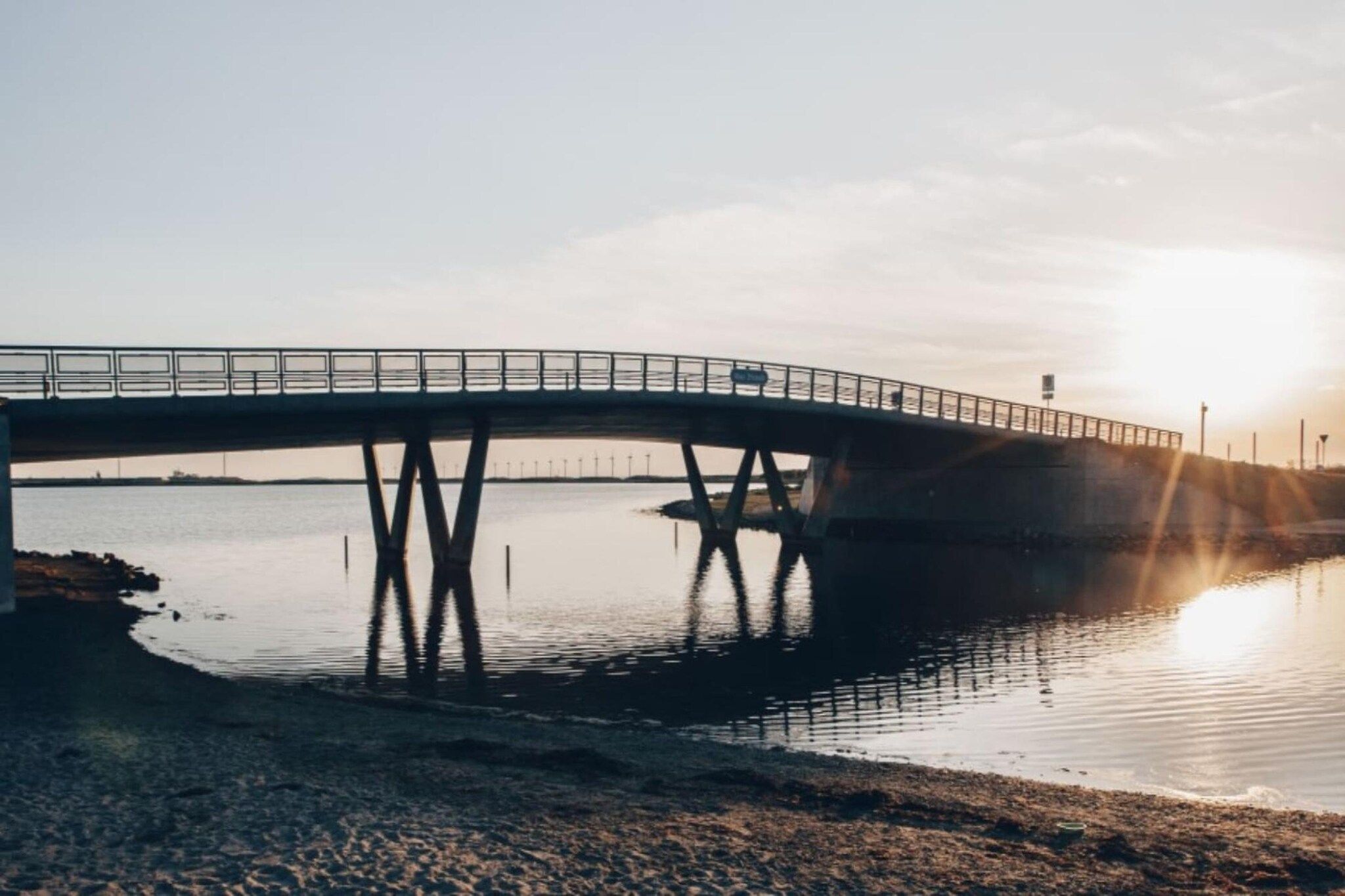 Un pont enjambant une étendue d’eau calme, sous un ciel dégagé.