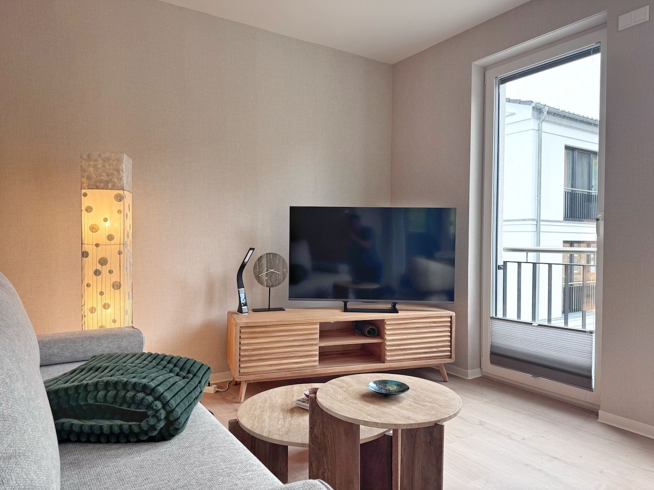 Ein modernes Wohnzimmer mit Flachbildfernseher, Holzunterhaltungseinheit und großem Fenster.