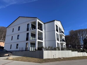 Ein mehrstöckiges Gebäude mit Balkonen, einem Parkplatz und blauem Himmel.