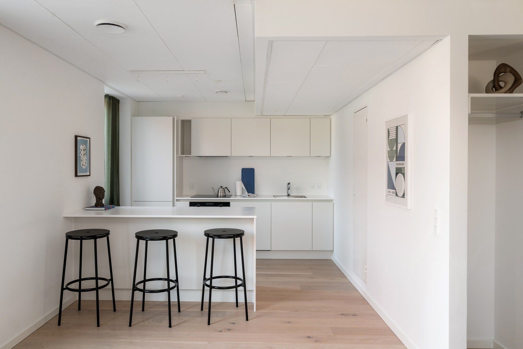 Et moderne køkken med en central ø, barstole og spiseplads.