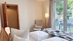 A hotel room with a bed, a chair, a lamp, and a view of the outside. - Kogge 6 Apartment - Sassnitz (Sassnitz)