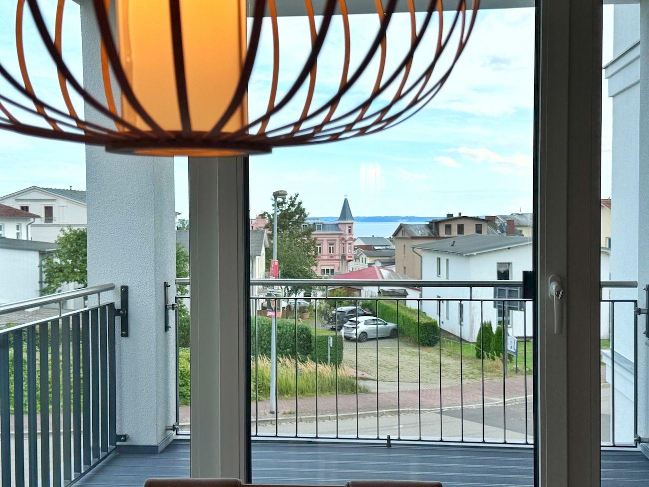 Ein Balkon mit Blick auf eine Wohnstraße, eine Kirche und ein Gewässer.
