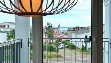Ein Balkon mit Blick auf eine Wohnstraße, eine Kirche und ein Gewässer.