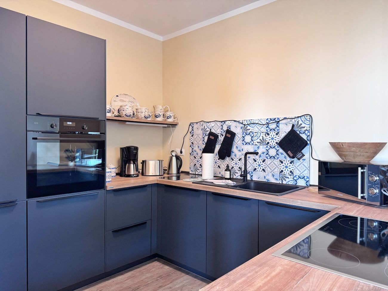 Eine moderne Küche mit integriertem Backofen, Kaffeemaschine und Wasserkocher.