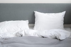 Ein Bett mit weißer Bettwäsche und einem grauen Kopfteil.