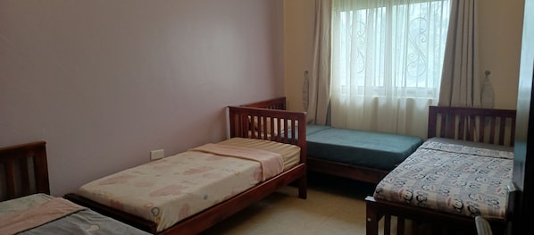 Une chambre avec deux lits simples, une fenêtre avec des rideaux et un radiateur.
