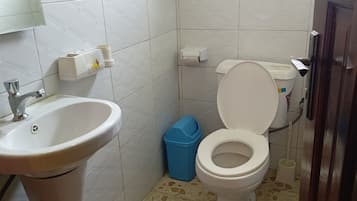 Une salle de bain avec un lavabo, des toilettes et une poubelle.