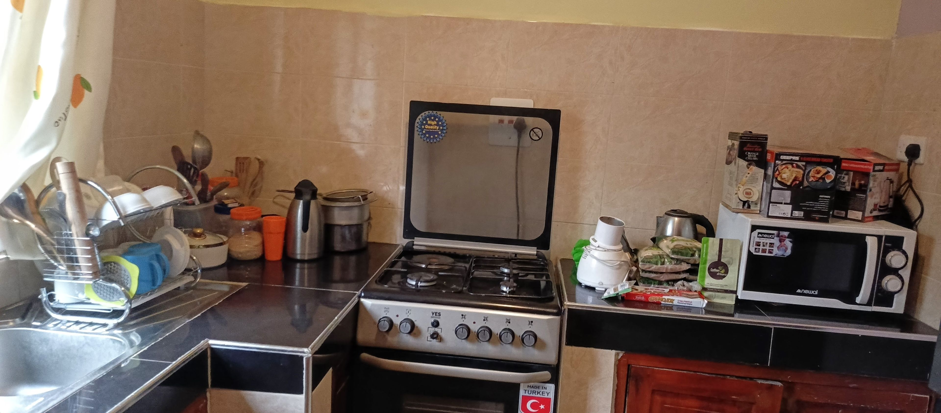 A compact kitchen with a stove, microwave, and various kitchen utensils.