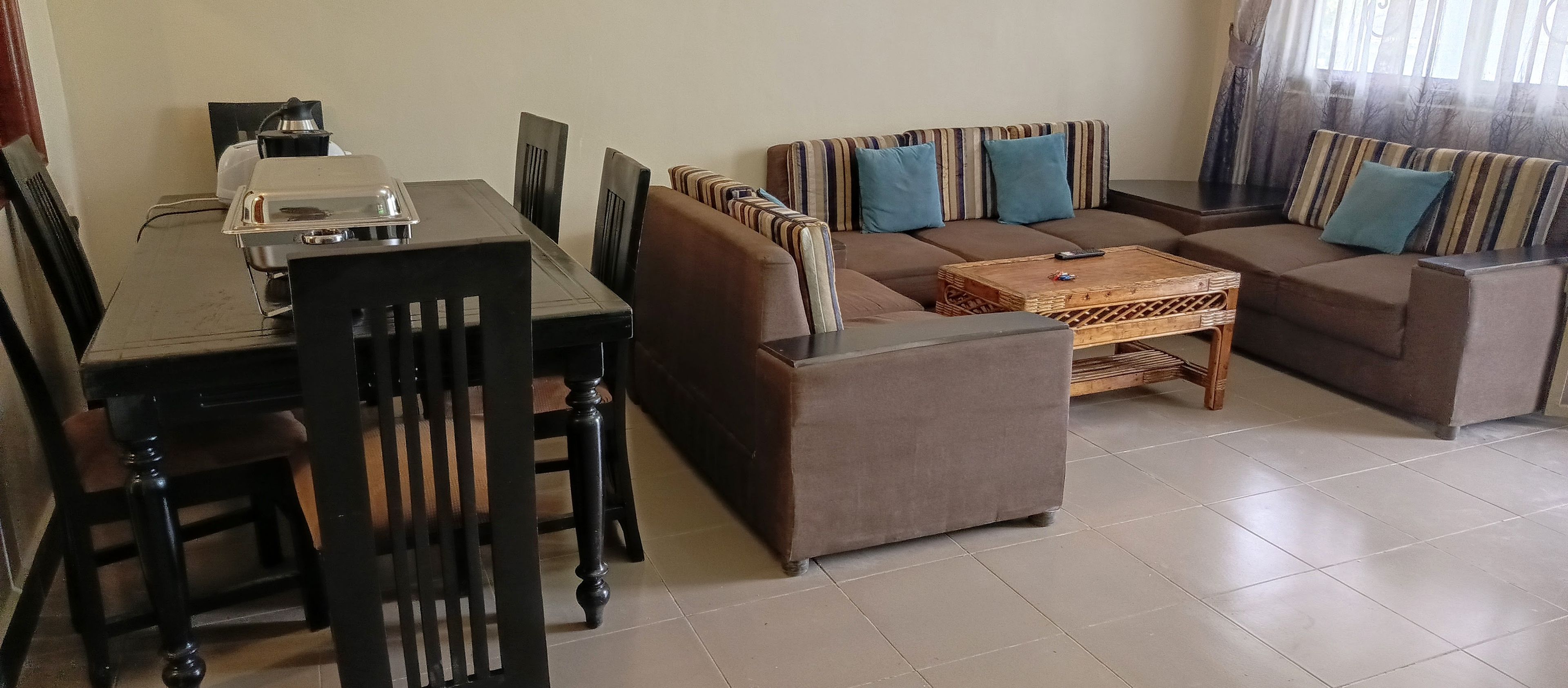 Ein Wohnzimmer mit einer Sofagarnitur, einem Couchtisch und einem Esstisch mit Stühlen.