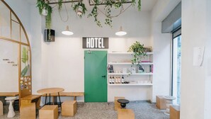 A hotel reception area with a green door, wooden furniture, and a sign that reads 'HOTEL'. - Dogpound Athens (Athens)