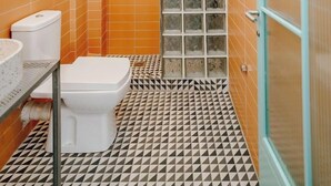 A bathroom with a toilet, sink, and a shower area with a glass door. - Dogpound Athens (Athens)