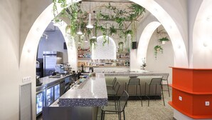 A bar area with a counter, seating, and hanging plants. - Dogpound Athens (Athens)