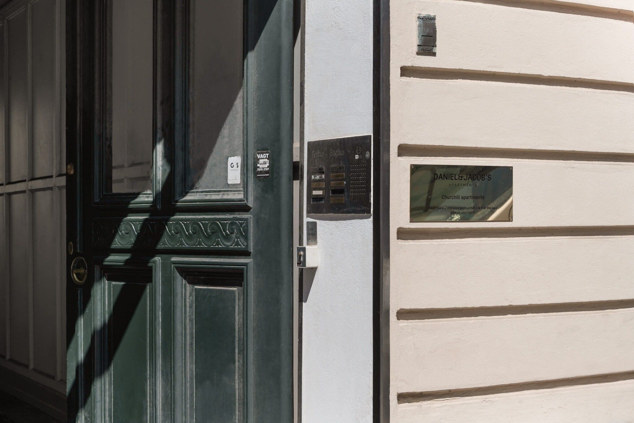 A building facade with a door, a mail slot, and a sign for 'DANIEL & JACOB'S APARTMENTS.'