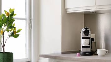 A kitchen with a coffee maker on the counter, a potted plant, and a window with a view.