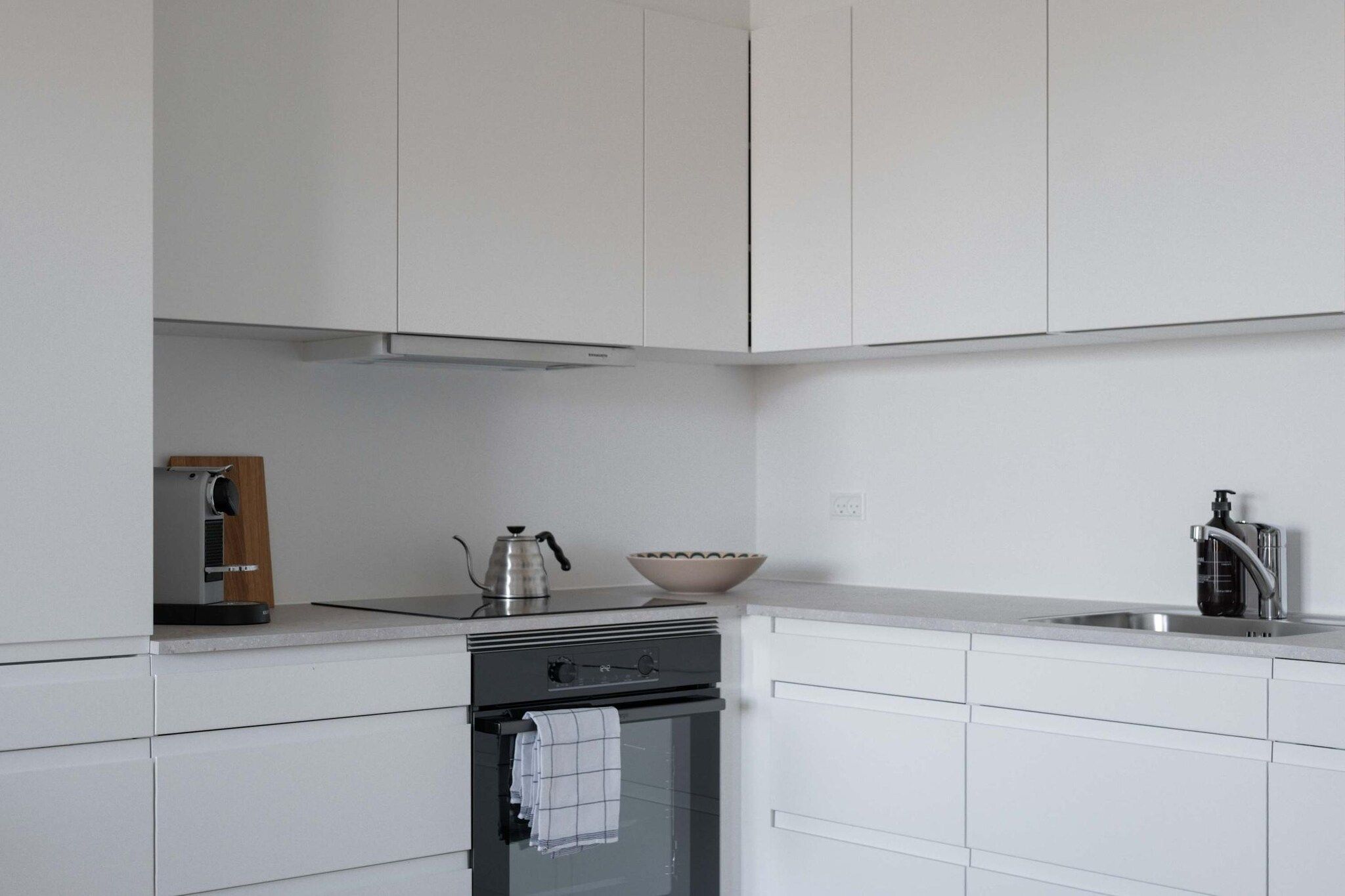Una cocina moderna con armarios blancos, estufa de acero inoxidable y horno empotrado.