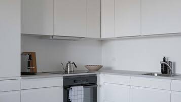 Una cocina moderna con armarios blancos, estufa de acero inoxidable y horno empotrado.