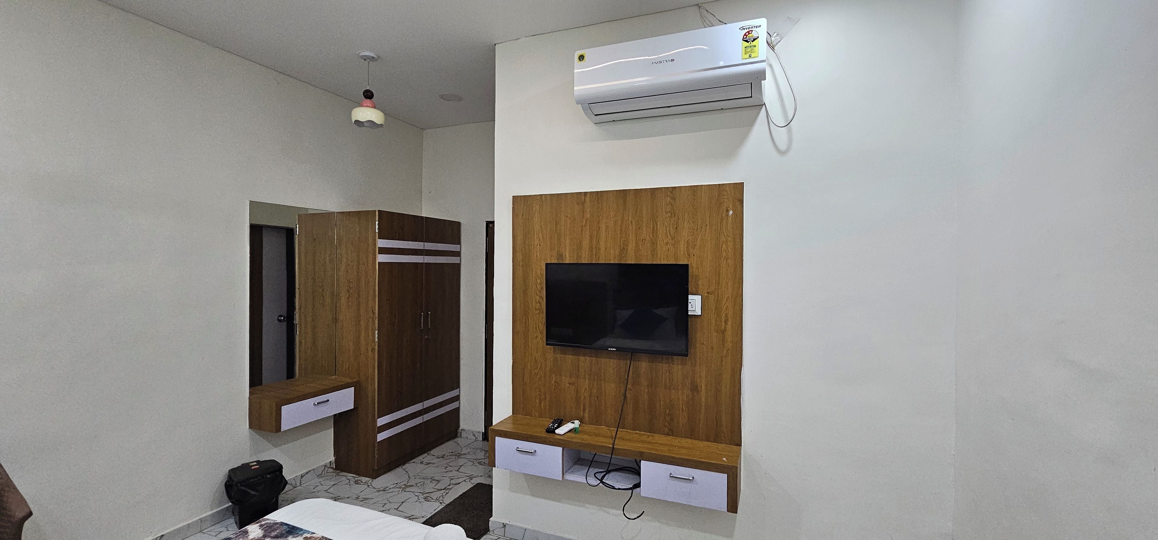 Una habitación con armario, televisión instalada en un panel de madera y equipo de aire acondicionado.