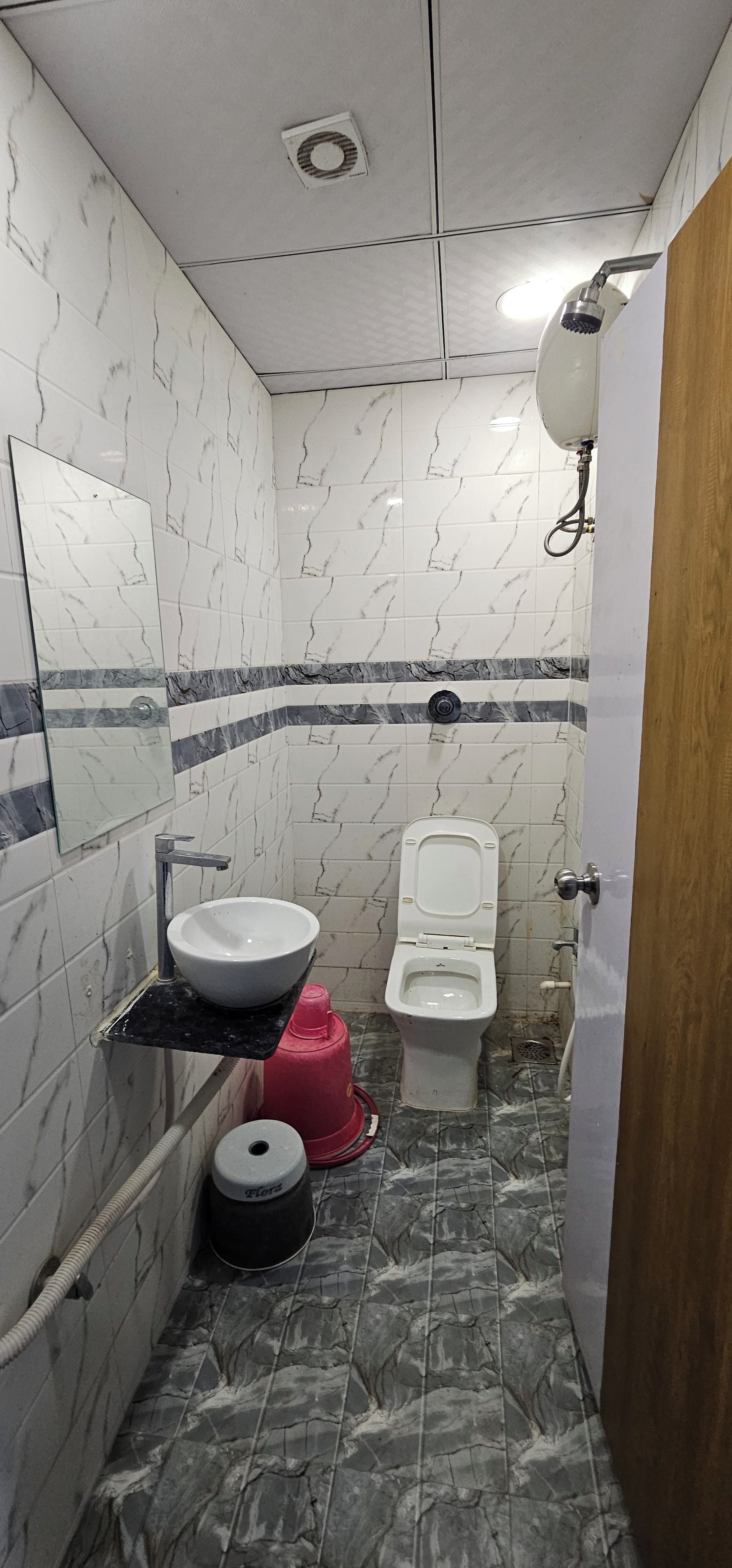 Un baño con lavamanos blanco, inodoro y espejo en la pared.