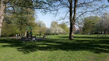 Un parque con un área de juegos, bancos y árboles.
