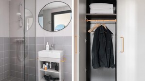Une salle de bain moderne avec une douche à parois de verre, un lavabo blanc agrémenté d’articles de toilette et un miroir.