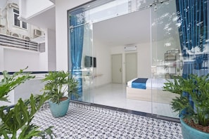 Une chambre d’hôtel moderne avec une porte en verre, un lit et une plante en pot.