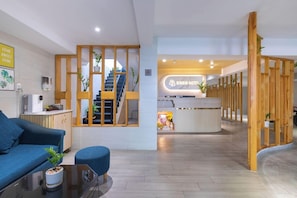 Un hall d’hôtel avec un comptoir d’accueil, un escalier, un canapé bleu et une table basse.