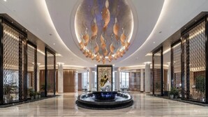Eine großzügige Lobby mit einer zentralen Fontäne, hohen Decken und moderner Einrichtung.