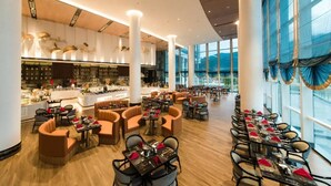 Eine großzügige Hotelhalle mit einer zentralen Bar, verschiedenen Sitzgelegenheiten und großen Fenstern für natürliches Licht.