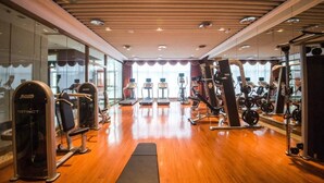 Ein Fitnessstudio mit Trainingsgeräten, Holzböden und großen Fenstern.