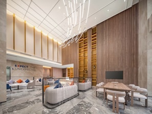 Um hall amplo com design moderno, com área de estar com sofás e cadeiras, painel de madeira com prateleiras embutidas e televisão de tela plana.
