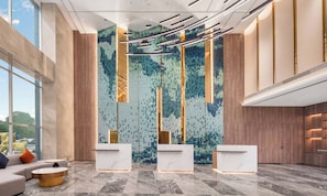 Uma área de recepção moderna com pisos de mármore, parede estampada e dois balcões de atendimento.
