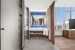 Uma casa de banho moderna com um espelho grande, uma pia e zona de duche.