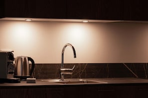 Een moderne keuken met een roestvrijstalen spoelbak, een waterkoker en een koffiezetapparaat.
