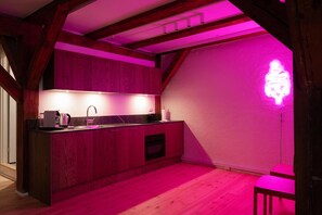 Eine Küche mit Holzausstattung, einem Spülbecken und einer Neonleuchte an der Wand.