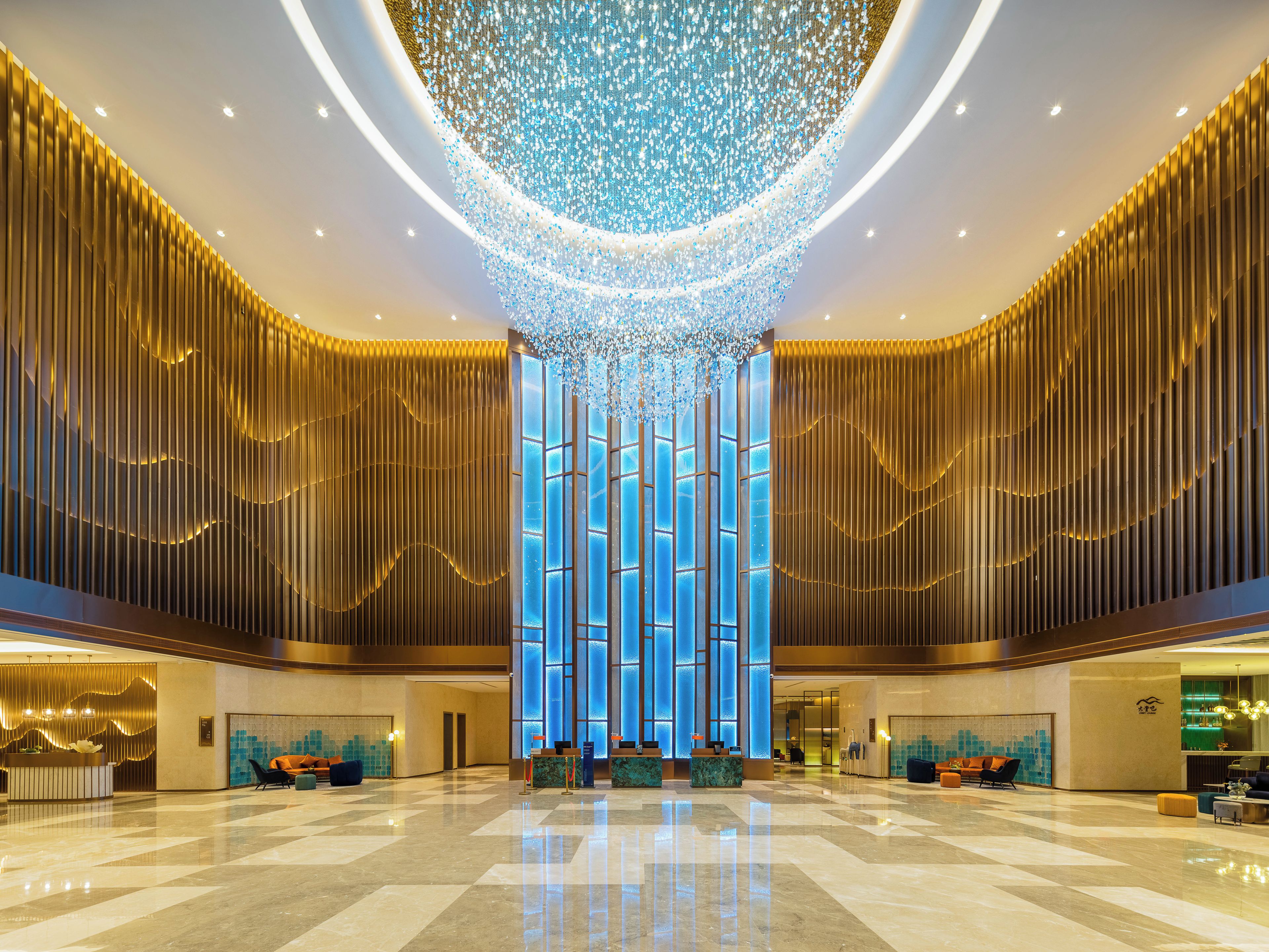 A spacious lobby with a high ceiling, a central column with vertical lighting, and a reception desk.
