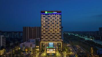 A tall hotel building with a Holiday Inn Express sign, surrounded by other buildings and a parking lot.