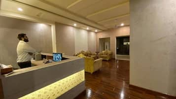 A reception area with a reception desk, a monitor, and a seating area with sofas.