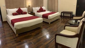 A hotel room with two beds, a seating area, and a small table.