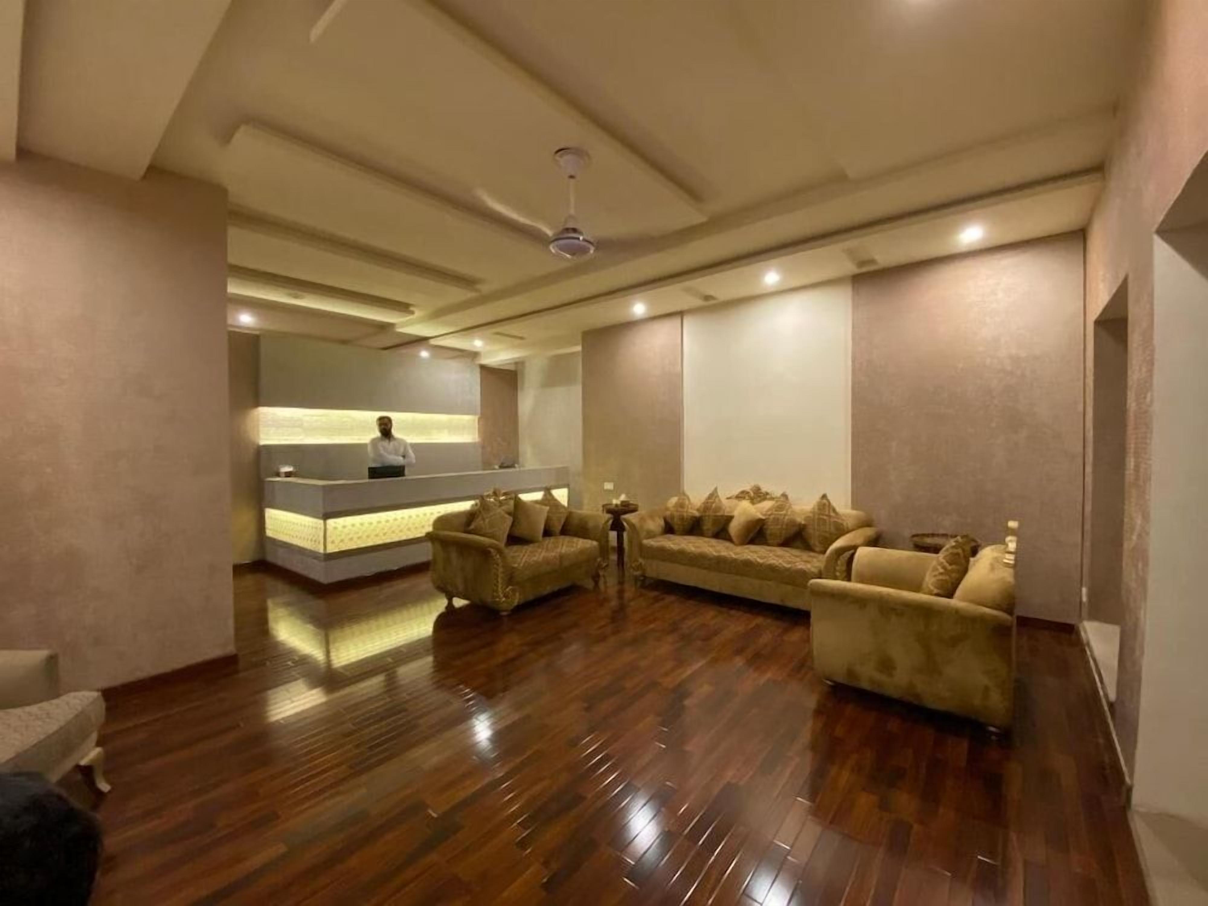 A spacious room with a reception desk, a sofa set, and a ceiling fan.